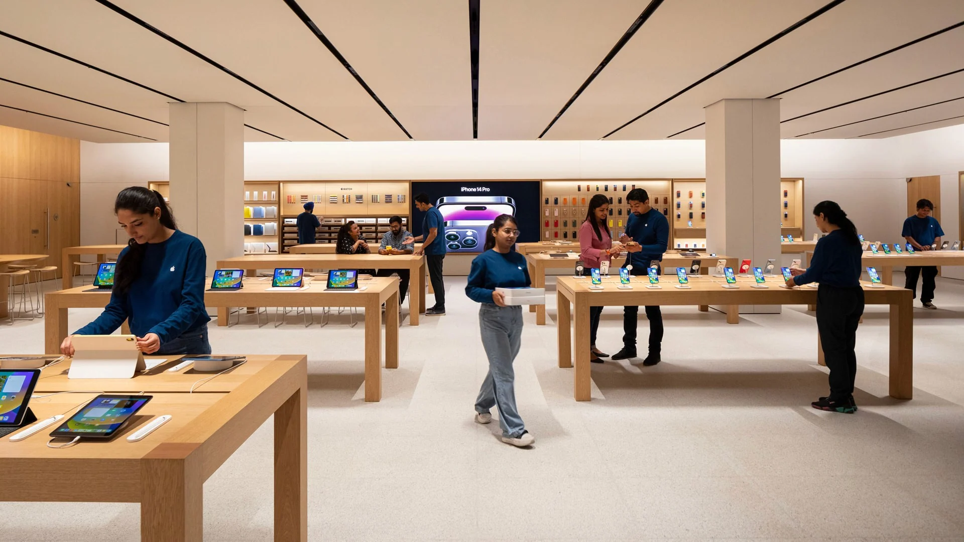 Customers and staff around Apple retail display tables